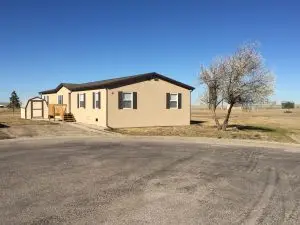 Single wide mobile home with open lot and nearby storage shed at Cottonwood Mobile Home Park in Wright Wyoming